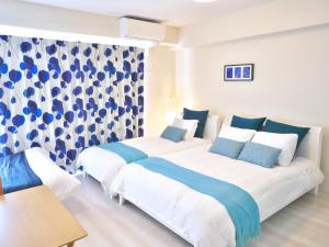 duas camas num quarto com azul e branco em ケイアイコンホテルズ ふくしあ801 em Chikusachō