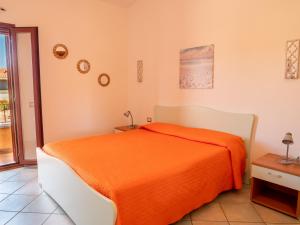 een slaapkamer met een bed met een oranje deken bij villetta a budoni con tutti i comfort in Budoni