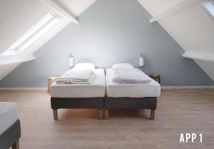 two twin beds in a room with an attic at Tussen Dijken in Hollum