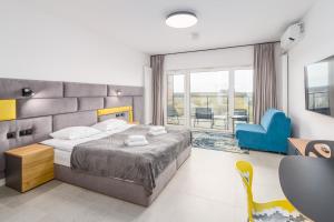 a bedroom with a large bed and a blue chair at Aquamarina Prima SEASIDE Apartments by the Beach by Renters in Międzyzdroje