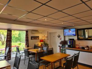 ein Restaurant mit Tischen und Stühlen sowie einem TV in der Unterkunft initial by balladins Bordeaux / Eysines in Eysines