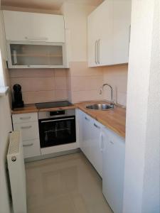 Elle comprend une petite cuisine avec des placards blancs et un évier. dans l'établissement Kod Lipe - Travnik, à Travnik