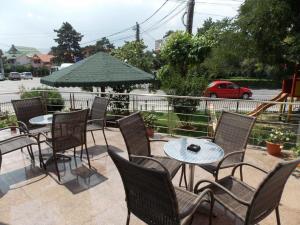 eine Terrasse mit Tischen und Stühlen und einem grünen Sonnenschirm in der Unterkunft Hotel Holiday in Eforie Nord