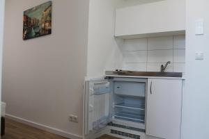a kitchen with a sink and an open refrigerator at Apartment Hotel am Sand 24H Self Check-in in Hamburg