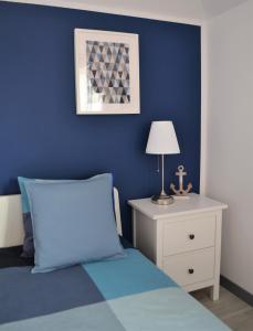 a blue bedroom with a bed and a table with a lamp at Międzywodami Jastarnia in Jastarnia