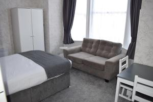 a bedroom with a bed and a couch and a chair at Cedar House, formerly Shamrock House in Llandudno