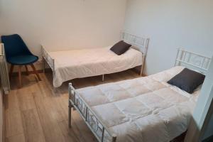 1 dormitorio con 2 camas y silla azul en LA CASA DE PECHABOU, en Péchabou