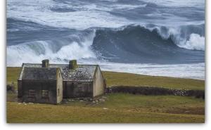 an old house on the beach with a large wave at Our View in Doolin