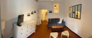 a living room with a tv and a blue couch at Maison de village au pays des lavandes à Valensole in Valensole +3 photos