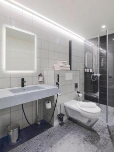 a bathroom with a sink and a toilet and a shower at VALO Hotel & Work Helsinki in Helsinki