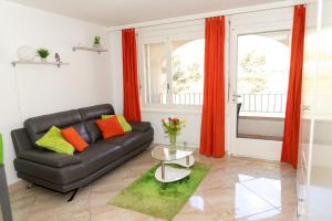 a living room with a black leather couch and orange curtains at Un moment de détente inoubliable Saillon-les-Bain in Saillon