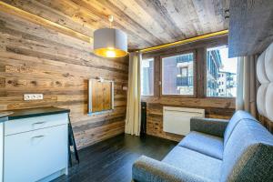 a living room with wooden walls and a blue couch at Magnifique petit studio 2-3 personnes dans l'Hyper Centre skis aux pieds vue front de neige in Val dʼIsère +16 photos