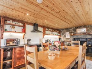 Il comprend une cuisine et une salle à manger avec une table en bois. dans l'établissement Kestrel Cottage, à Rogart