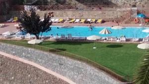 una gran piscina con sillas y sombrillas en Casa Rural Las Cáscaras Tejeda Gran Canaria, en Tejeda