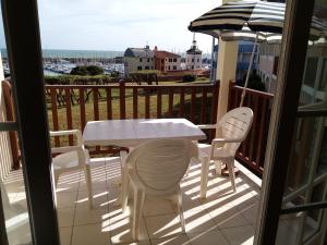 een tafel en stoelen op een balkon met uitzicht op de oceaan bij appartement vue sur mer in Talmont