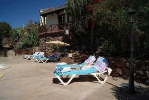 two lounge chairs and an umbrella in a patio at Casa Rural El Olivar La Almazara in Santa Lucía