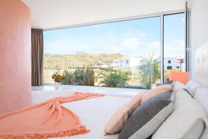 a bedroom with a large window and a couch at AQUABLANCA Suite Pool Deluxe en Punta Mujeres in Punta de Mujeres