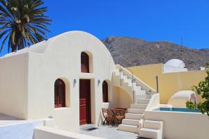 a white building with stairs and a palm tree at Dreamer's secret villa in Emporio Santorini