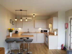 a kitchen with white cabinets and a island with bar stools at Lindisfarne Self Catering in Navershaw