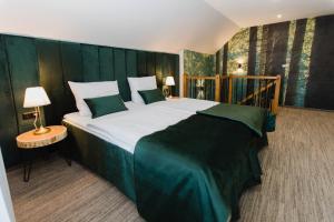 ein Schlafzimmer mit einem großen Bett mit grünem Kopfteil in der Unterkunft Hotel Kotarz Spa&Wellness in Brenna