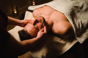 a man laying on a bed getting his hair brushed at Hotel Kotarz Spa&Wellness in Brenna