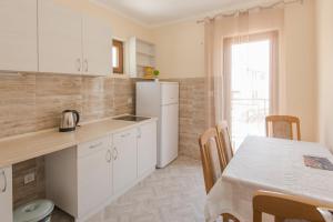 uma cozinha com uma mesa e um frigorífico branco em Apartmani Miljenovic em Kotor