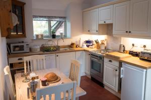 uma cozinha com armários brancos e uma mesa com pão em Courtyard Cottage em Oswestry