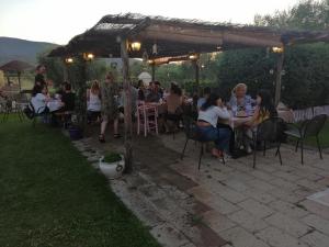 a group of people sitting at tables under a pergola at Podere Montecorno in Alberese