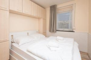 een wit bed in een kamer met een raam bij Holidayhome - Morgensterwei 24 Kortgene in Kortgene