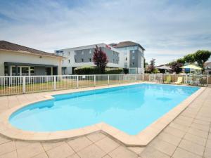 a large swimming pool with a fence and a building at ibis budget Cahors in Cahors