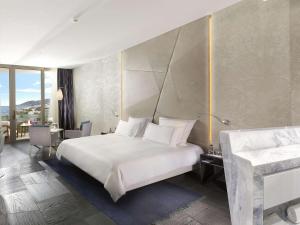 Schlafzimmer mit einem großen weißen Bett und einem Schreibtisch in der Unterkunft Swissôtel Resort Bodrum Beach in Turgutreis