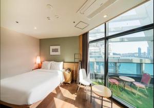 een hotelkamer met een bed en een groot raam bij Gwangalli Hotel primavera in Busan in Busan