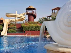 a large swimming pool with a large clock tower at Mövenpick Resort & Spa Tala Bay Aqaba in Aqaba