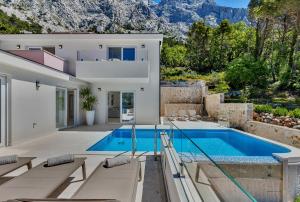 uma villa com uma piscina com montanhas ao fundo em Villa Prestige em Baska Voda