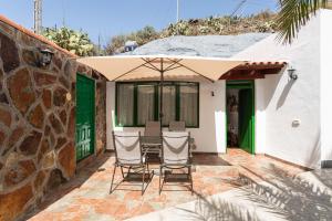 une terrasse avec des chaises et une table avec un parasol dans l'établissement Sunset Views Terrace 2BR Cave House - Parking, à Santa Brígida