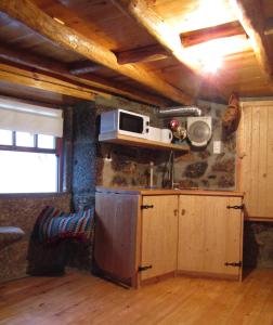 uma cozinha com um micro-ondas no topo de uma parede em Casa Encantada - Alvoco da Serra em Alvoco da Serra