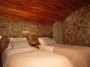 duas camas num quarto com uma parede de pedra em Casa Encantada - Alvoco da Serra em Alvoco da Serra