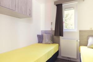 a small bedroom with two beds and a window at Kievit 4 persons in Rijssen