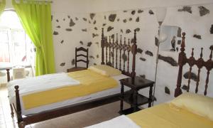 a bedroom with two beds and a green curtain at Vivenda Flores - Casa Hortensia in Lomba