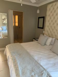 een slaapkamer met een groot wit bed en een raam bij Sharwood Place in Port Elizabeth