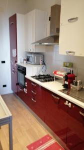 uma cozinha com armários vermelhos e um forno com placa de fogão em Casa Posa em Bari