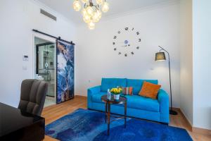 a blue couch in a living room with a clock on the wall at Lisbon 5 Hotel in Lisbon