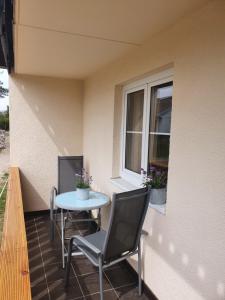 a patio with two chairs and a table and a window at Am Walde in Trassenheide +3 photos