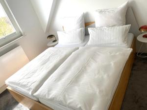 uma cama num quarto com lençóis brancos e almofadas em Ferienwohnung Möwe 14 em Schleswig