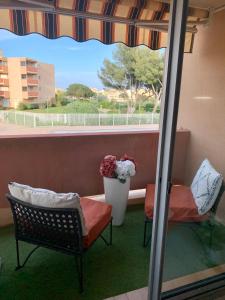 un balcón con 2 sillas y un jarrón con flores en My Little Provence Bormes Les Mimosas en Bormes-les-Mimosas