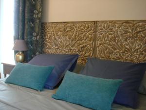 a bed with two blue pillows and a wooden headboard at Moulin de Giboudet Chambres d'hôtes in Bazainville