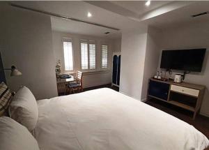 a bedroom with a large white bed and a flat screen tv at 朵兒dor韓國汗蒸幕 동대문점 商務旅店 in Taipei