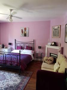 a bedroom with pink walls and a bed and a couch at Les Charrons in Ségur-le-Château