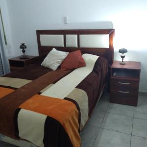 a bedroom with two beds and a night stand with two lamps at Departamentos La Tita in Concepción del Uruguay