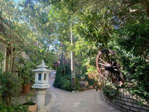 a garden with a statue of a wooden wheel and trees at The Little Hideaway Guesthouse in Stellenbosch